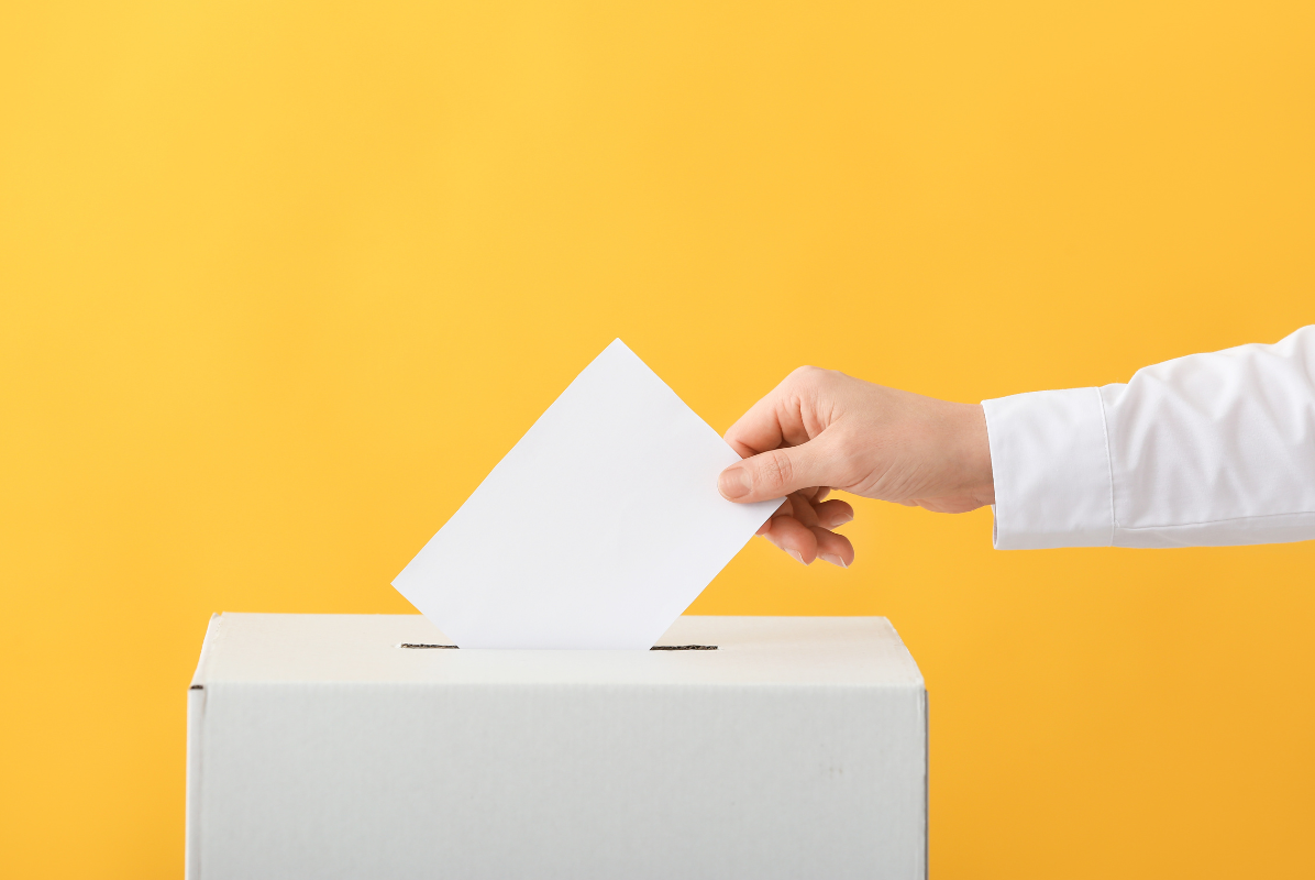 A hand putting a ballot in a ballot box